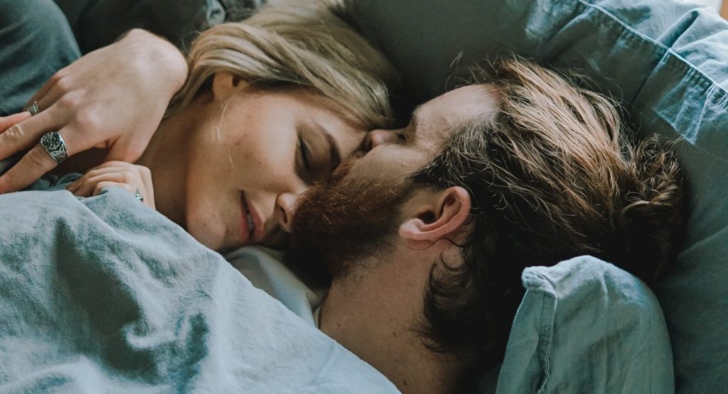 Man and woman in bed kissing on forehead