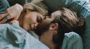 Man and woman in bed kissing on forehead
