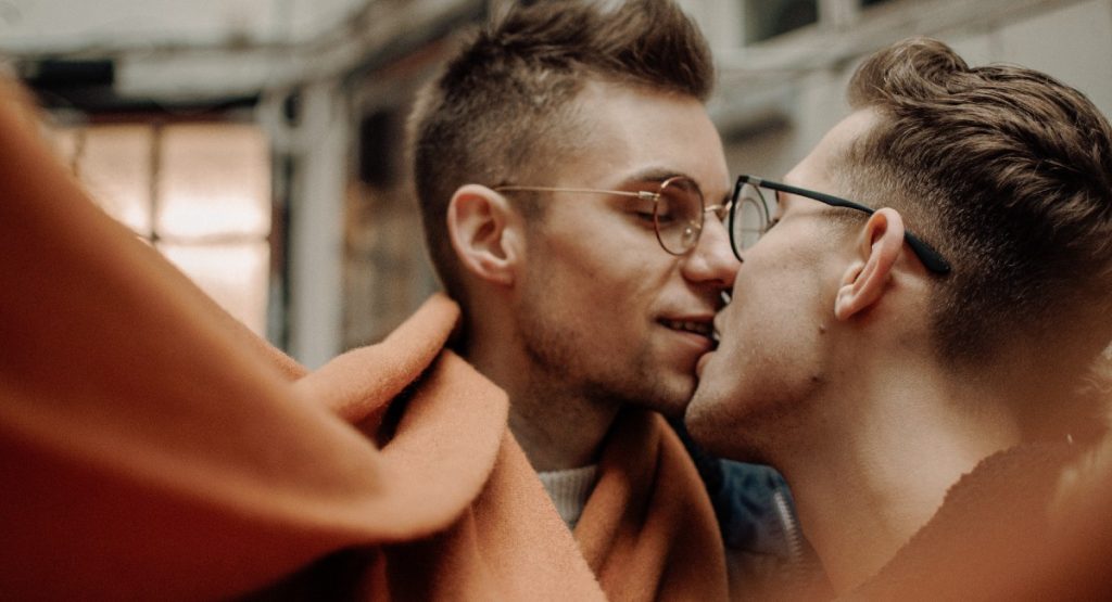Two young guys kissing